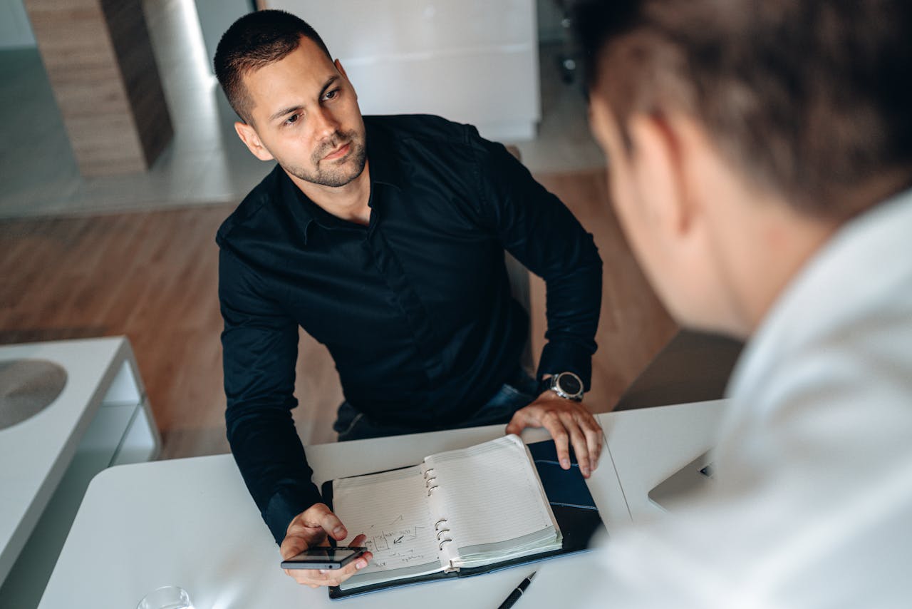 Two professionals engaged in a focused business meeting with a notebook and smartphone.